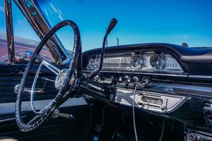 Close-up view of a vintage car dashboard and steering wheel against blue sky.