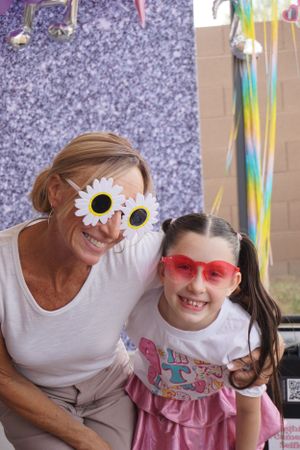 Fun party scene with people wearing novelty sunglasses and colorful decorations.
