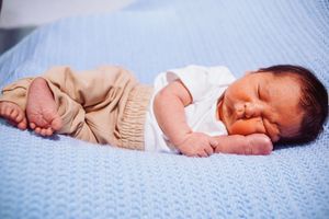 Sleeping infant lying on blue textured blanket in peaceful repose.