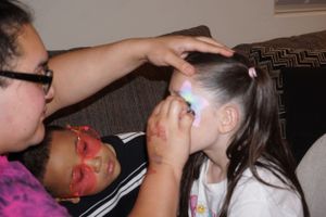 Children getting face paint applied during what appears to be a party or event.