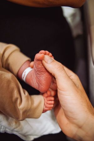 Close-up of hands gently holding a newborn baby's feet.