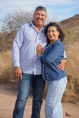 Casual outdoor portrait of a couple embracing on a desert trail.