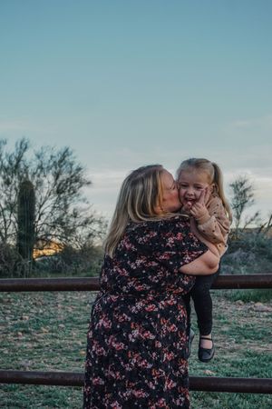 Friends sharing a joyful moment together by a rustic fence at sunset.