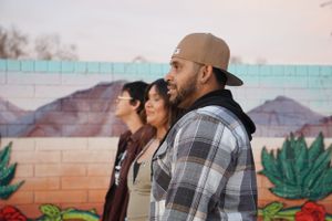 Couple sharing an intimate moment in front of a painted desert mural wall.