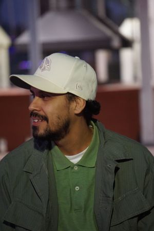 Person in green polo shirt and jacket smiling outdoors.