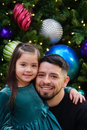 Holiday portrait with festive ornaments and Christmas tree lights in the background.