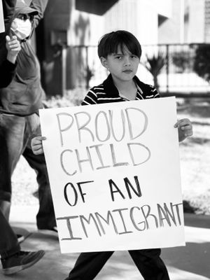 Signs being held up with text about being proud of an immigrant child.