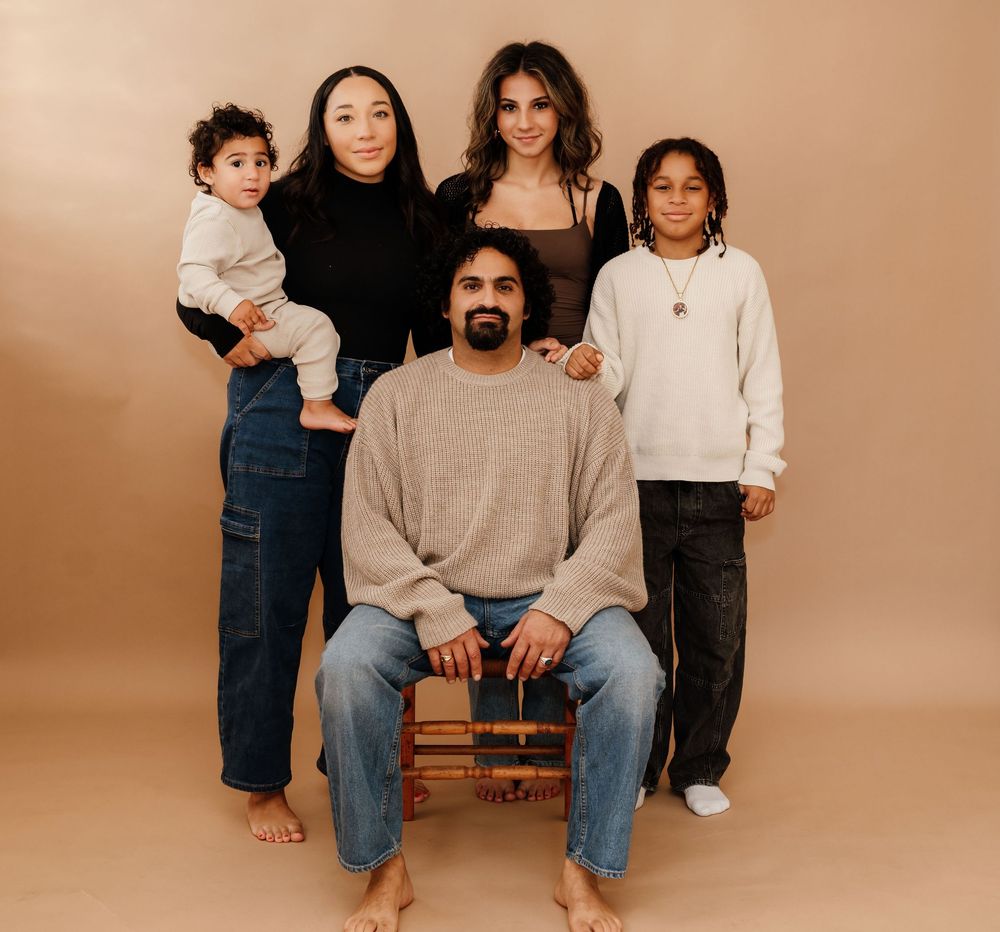 Studio portrait series against beige backdrop showing casual family poses on wooden bench.