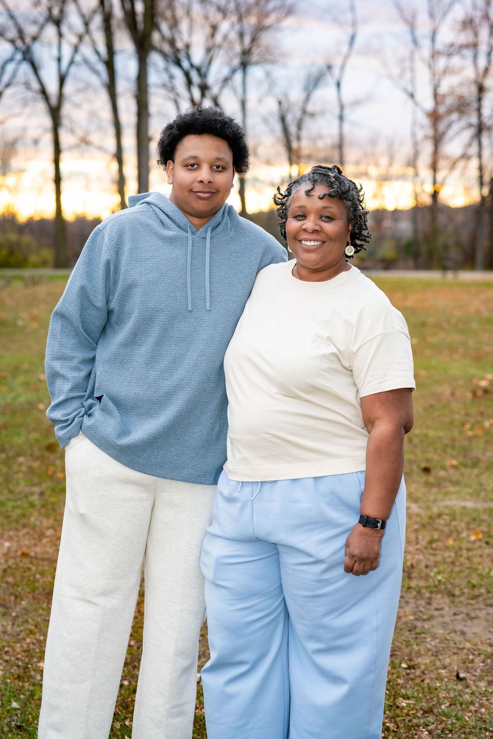 Family photos in coordinated casual outfits of blue, white and cream tones against autumn backdrop.