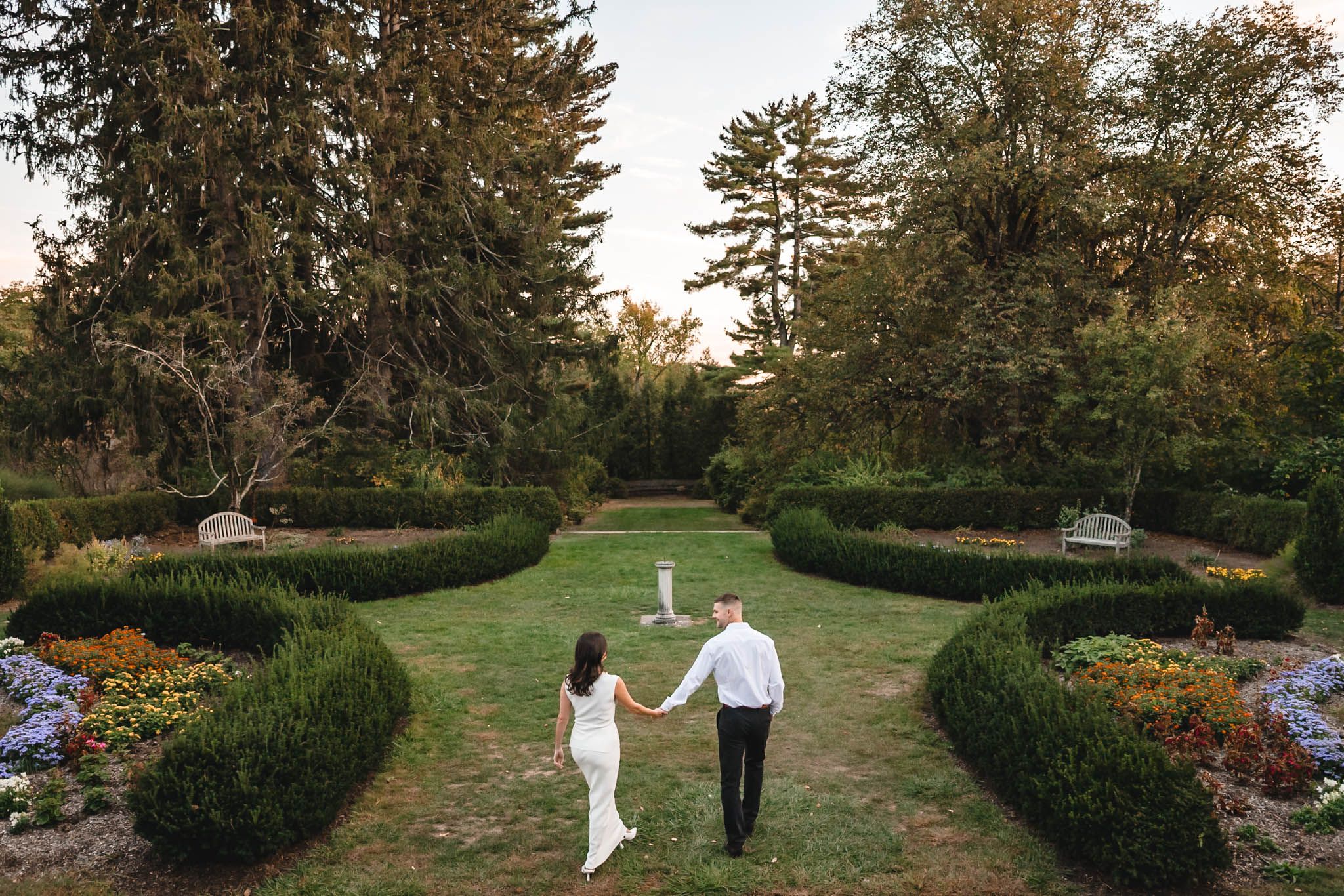 Elegant garden pathway lined with manicured hedges and natural landscaping at golden hour.