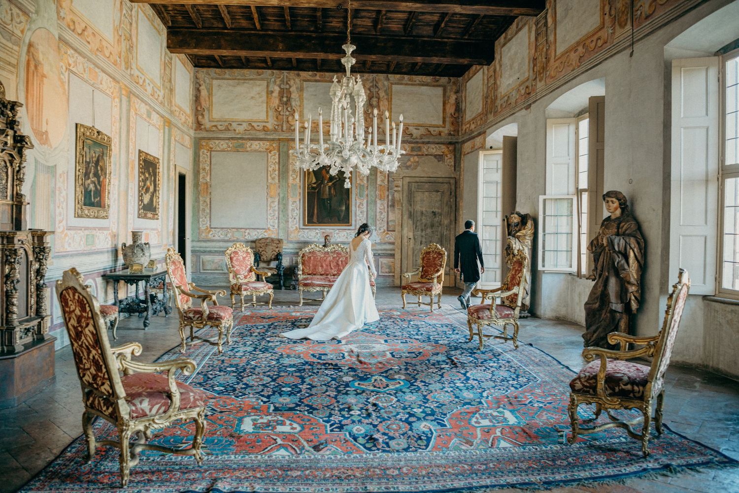 Elegante camera vintage con lampadario di cristallo, mobili decorati e tappeto persiano blu in uno storico interno di un palazzo europeo.