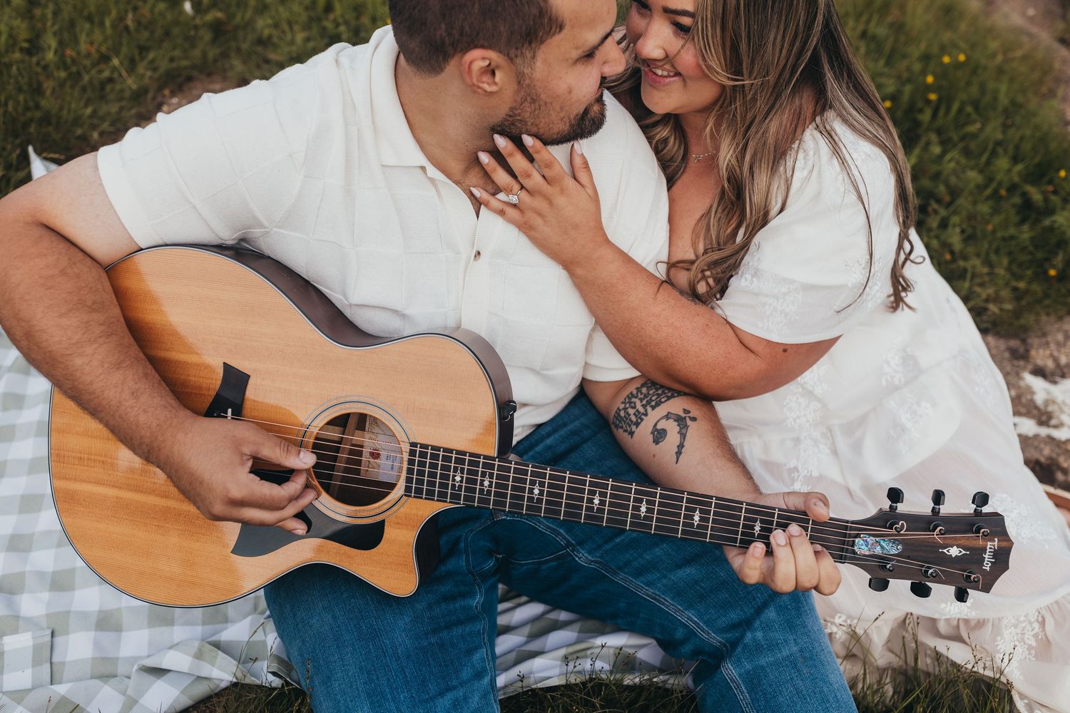 Couple sharing an intimate moment outdoors with acoustic guitar.