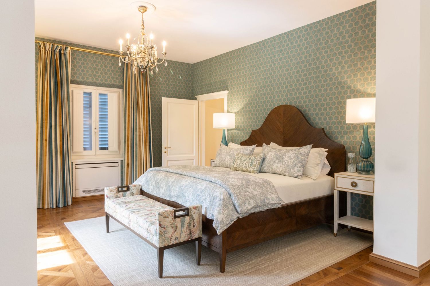 Tuscany property photographer. Bedroom interior with mint green walls, hardwood flooring, and natural light streaming through windows.