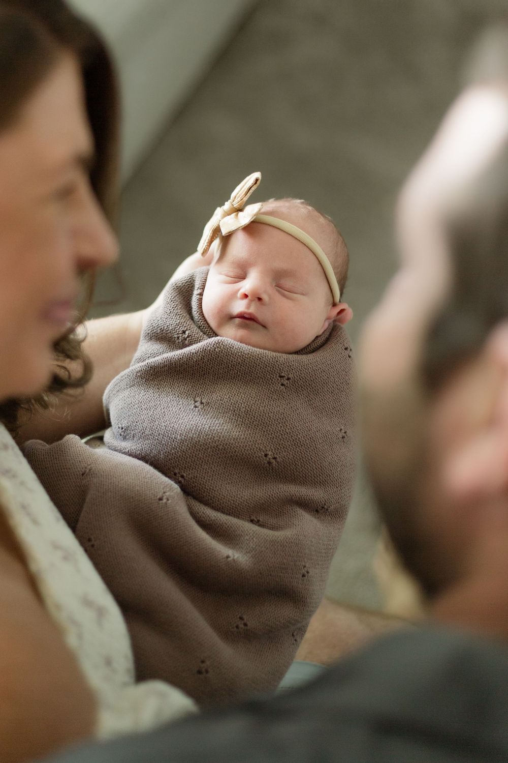 Close-up view of sleeping newborn baby swaddled in soft gray blanket.