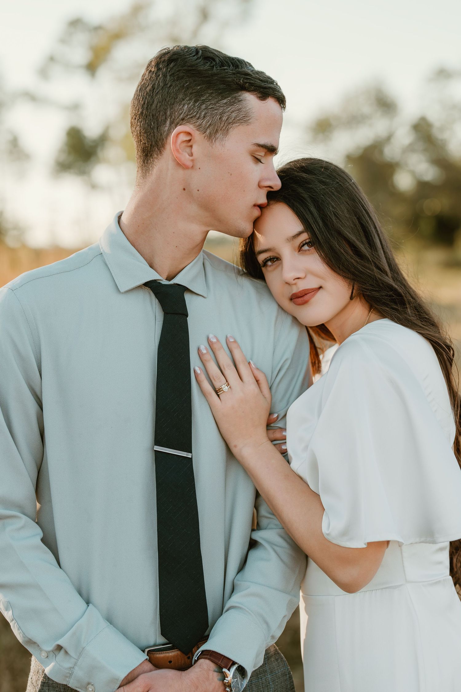 A romantic couple in light colored clothing share intimate moments across four connected photos outdoors.