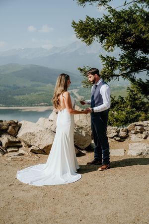 Wedding ceremony by a scenic lakeside with mountains in the background.