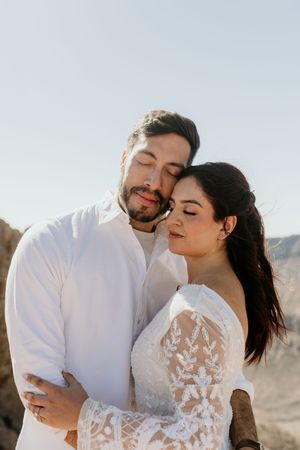 Romantic wedding photos showing tender moments between a couple in a desert landscape.