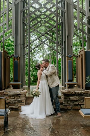 Wedding portraits inside a modern glass chapel with stone details and geometric architecture.