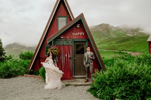 Red A-frame cabin wedding venue nestled in green mountain landscape.