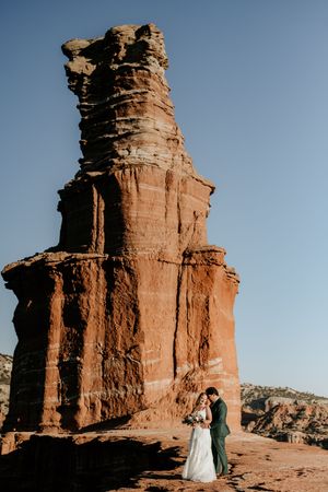 Wedding couple silhouetted against majestic red rock formations in the desert.
