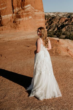 A flowing white wedding dress photographed against red rock formations in the desert.