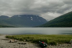 A serene mountain lake surrounded by snow-capped peaks under moody clouds.