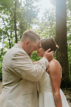 Tender wedding moment captured in a serene forest setting.