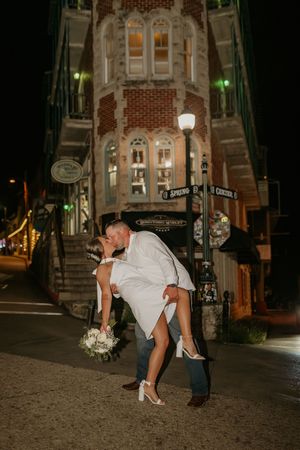 A romantic nighttime street scene in front of a historic brick building with glowing lamps.