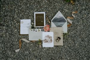 Wedding invitation suite and paper details laid out on a textured gray surface.
