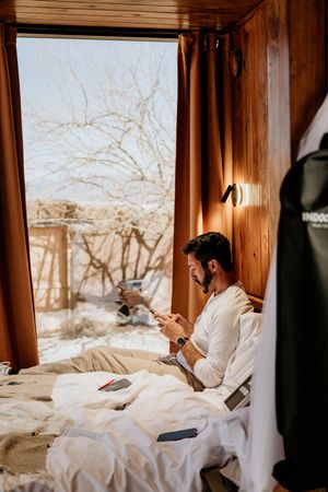 Cozy morning scene in a cabin with white bedding and wooden walls.