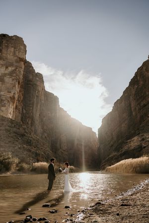 Dramatic wedding photos in a sunlit canyon with towering rock walls.