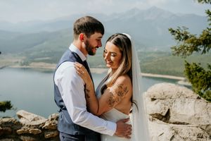 A tender moment between newlyweds overlooking a mountain lake vista.