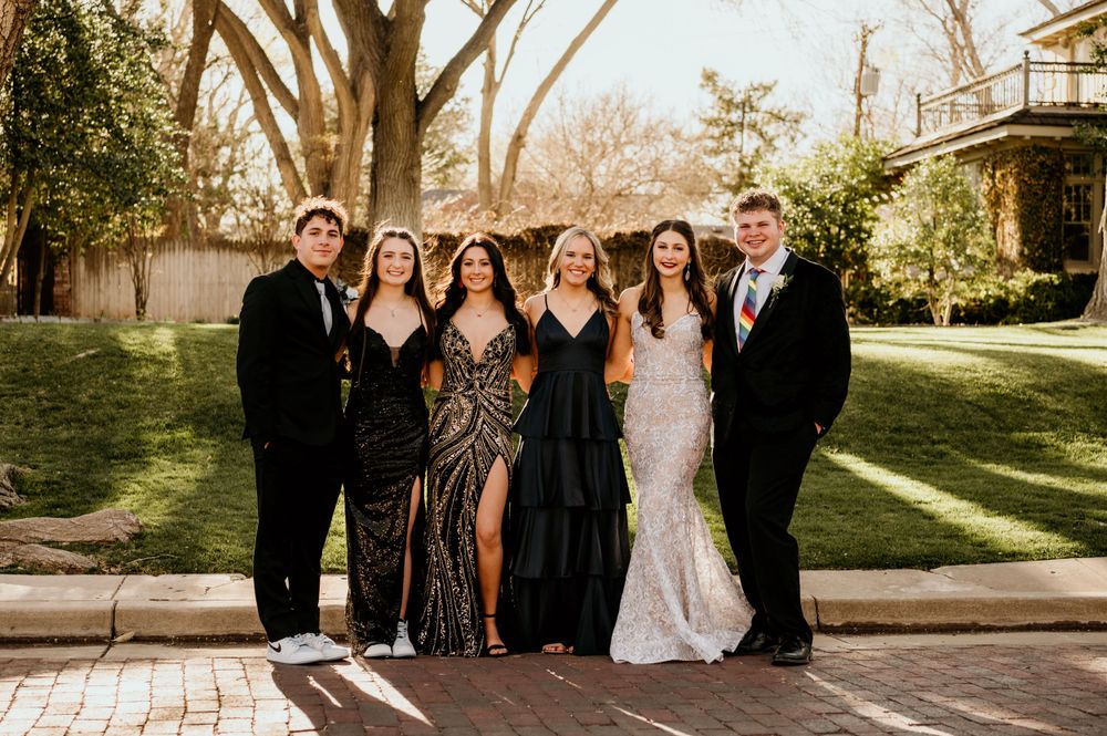 A formal group photo taken outdoors with people dressed in elegant attire.