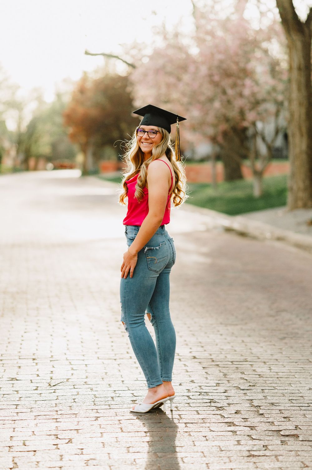 Graduation portraits on a cobblestone path with cherry blossoms in the background.