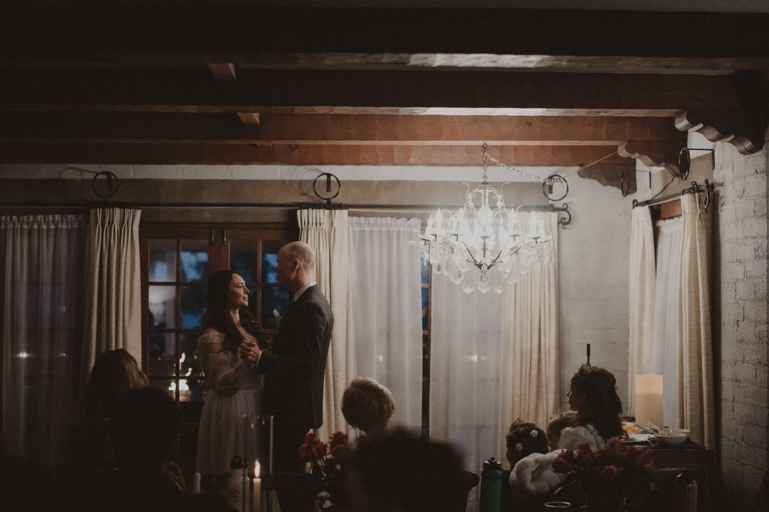 A luxurious banquet hall with crystal chandeliers, elegant drapes, and tables set for a formal event.