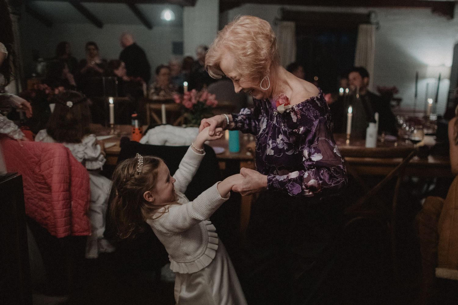 Couples dancing together at an elegant indoor wedding reception with soft lighting and curtained windows.