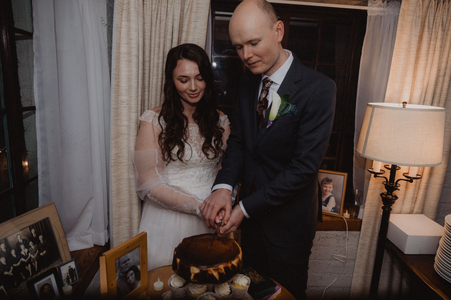 Guests at an elegant indoor wedding reception share intimate moments in a dimly lit venue.