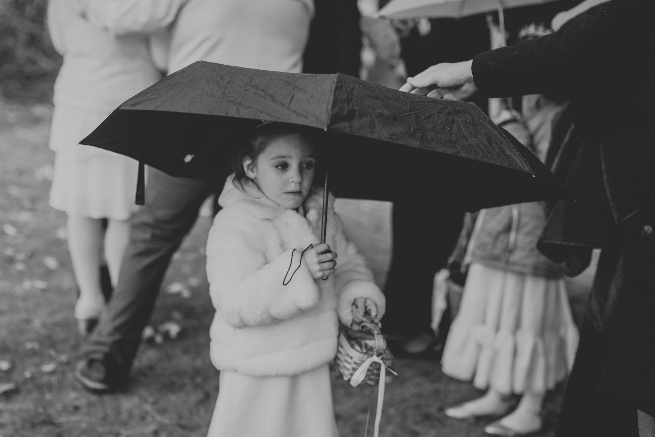 A black and white graduation ceremony photo shows students in caps and gowns walking in a procession line outdoors.