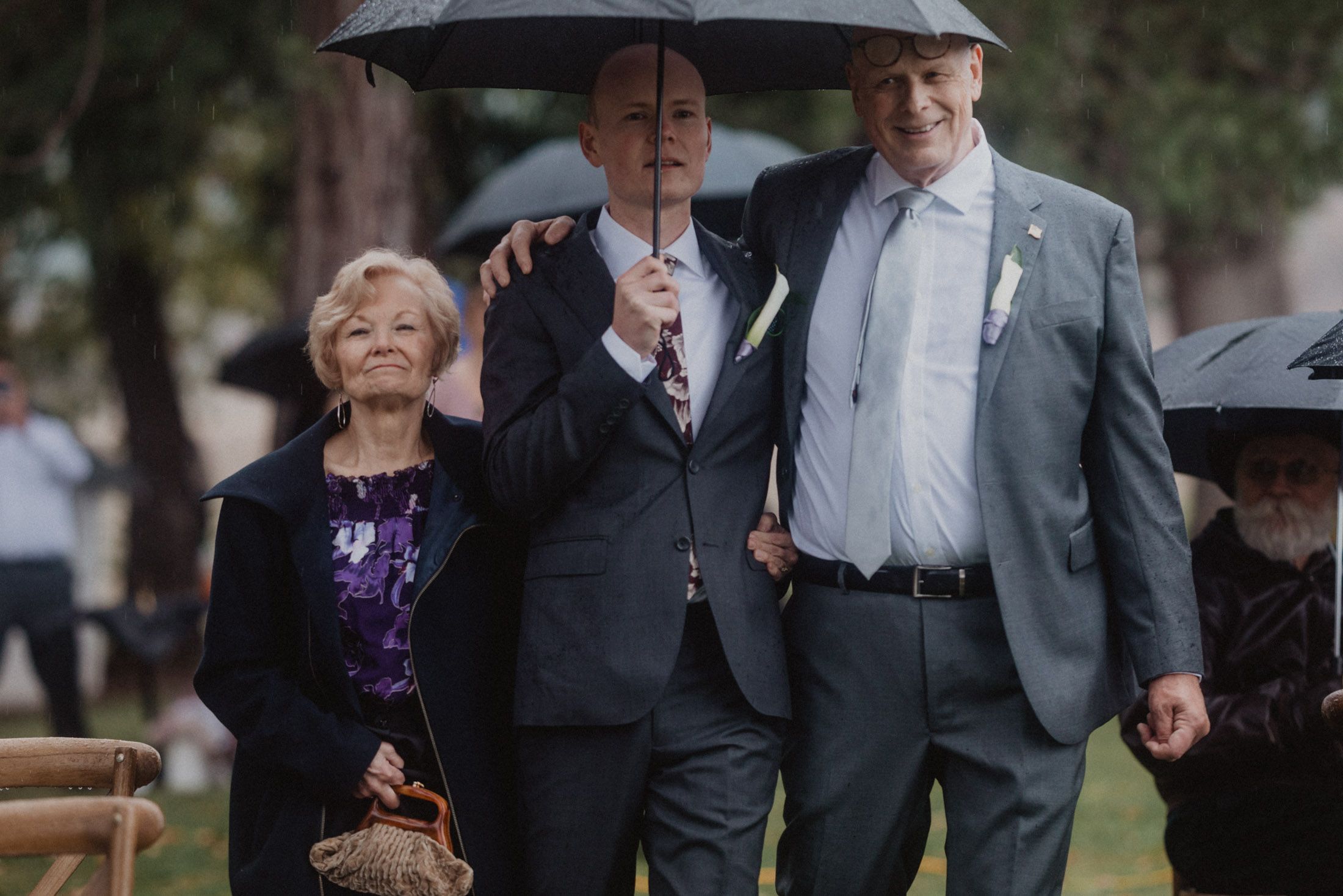 Guests with umbrellas mingle at an outdoor event on a misty autumn day.