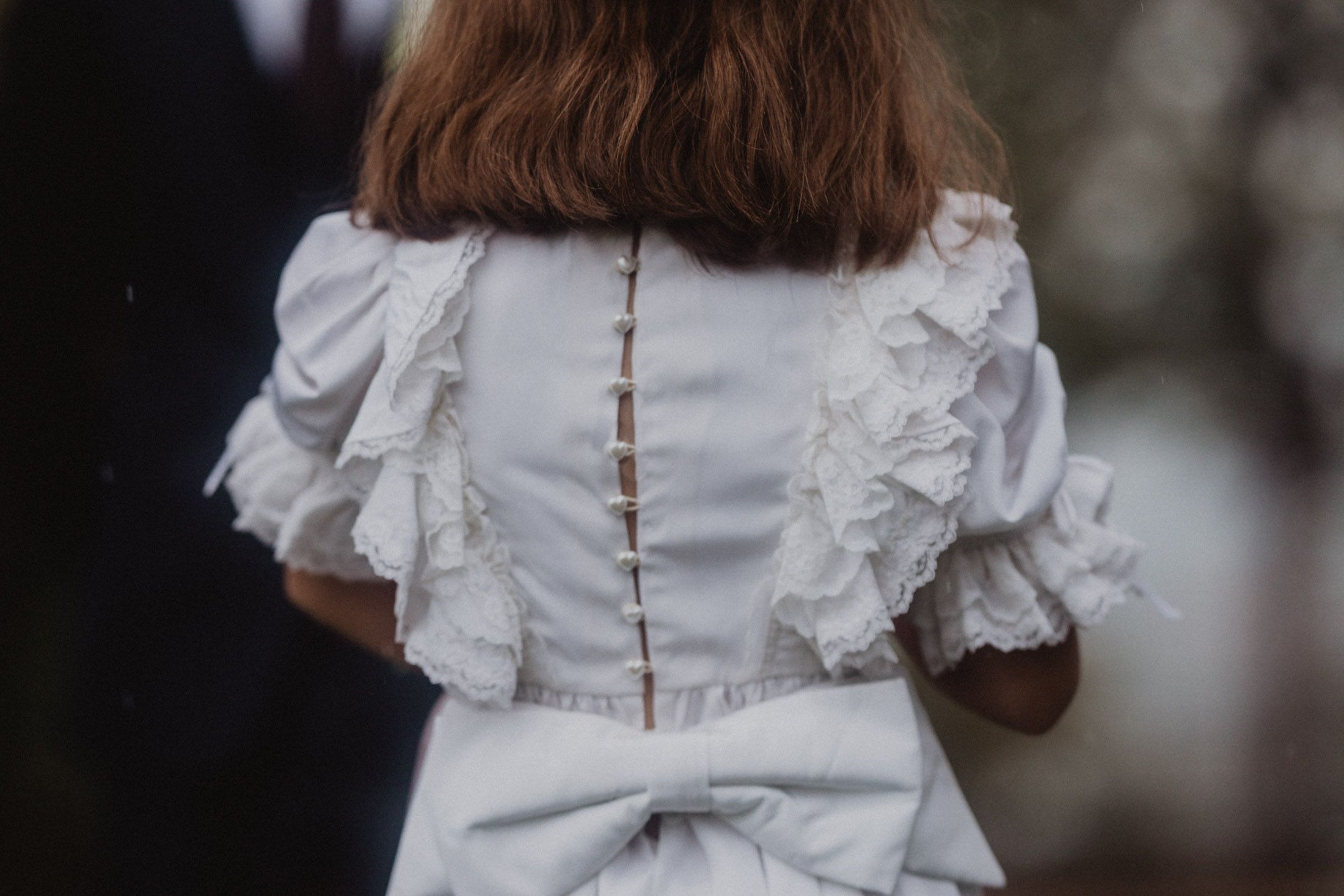 Close-up view of a white wedding dress with delicate lace details and ruffled sleeves.