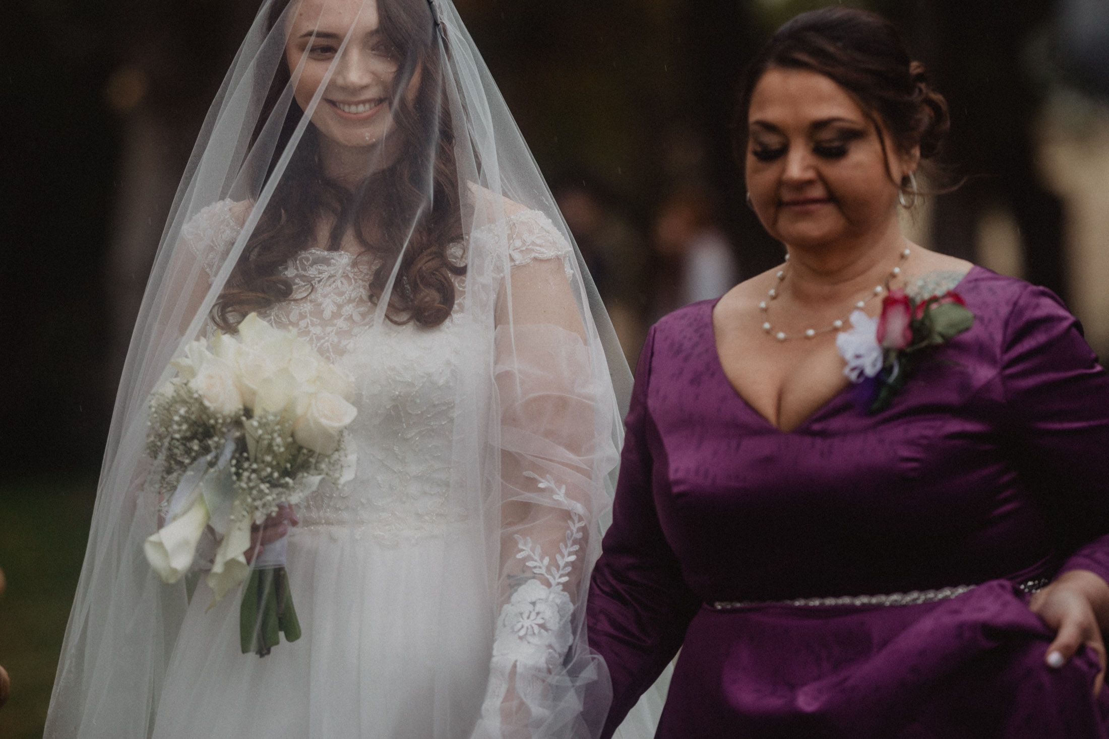 Wedding party members in purple and white attire gather during an outdoor autumn ceremony.