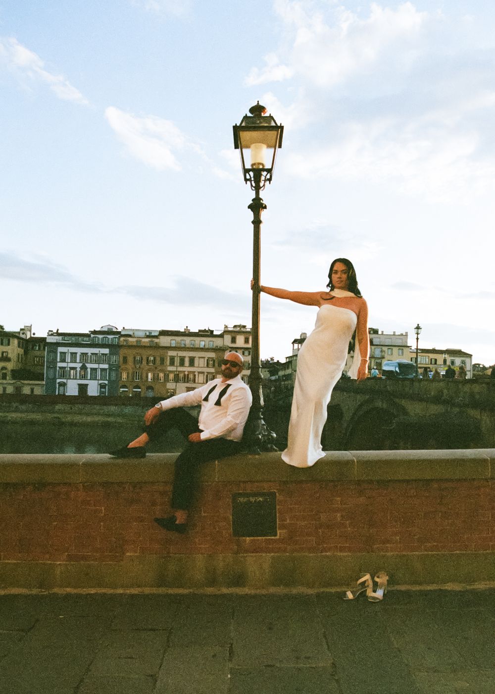 A sequence of artistic photos showing someone in white clothing posing playfully on a brick wall with a street lamp.