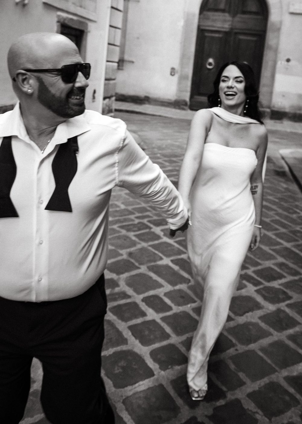 A sequence of black and white photos showing people in formal attire dancing and moving on a cobblestone courtyard.