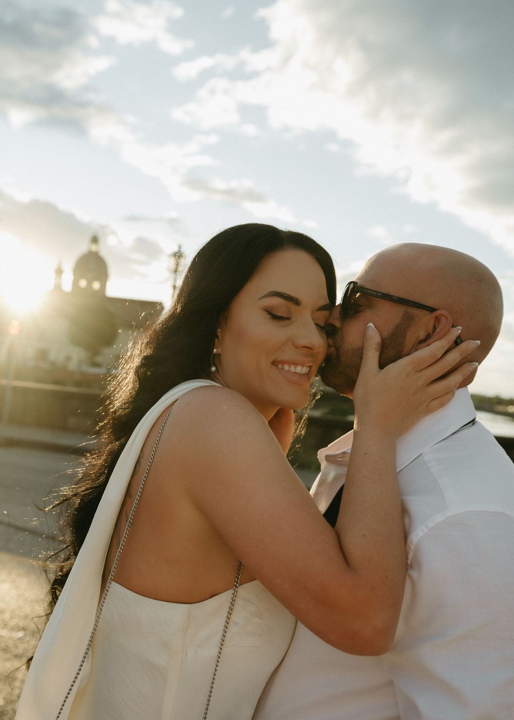A romantic sunset beach photoshoot featuring a couple in wedding attire embracing by the water.