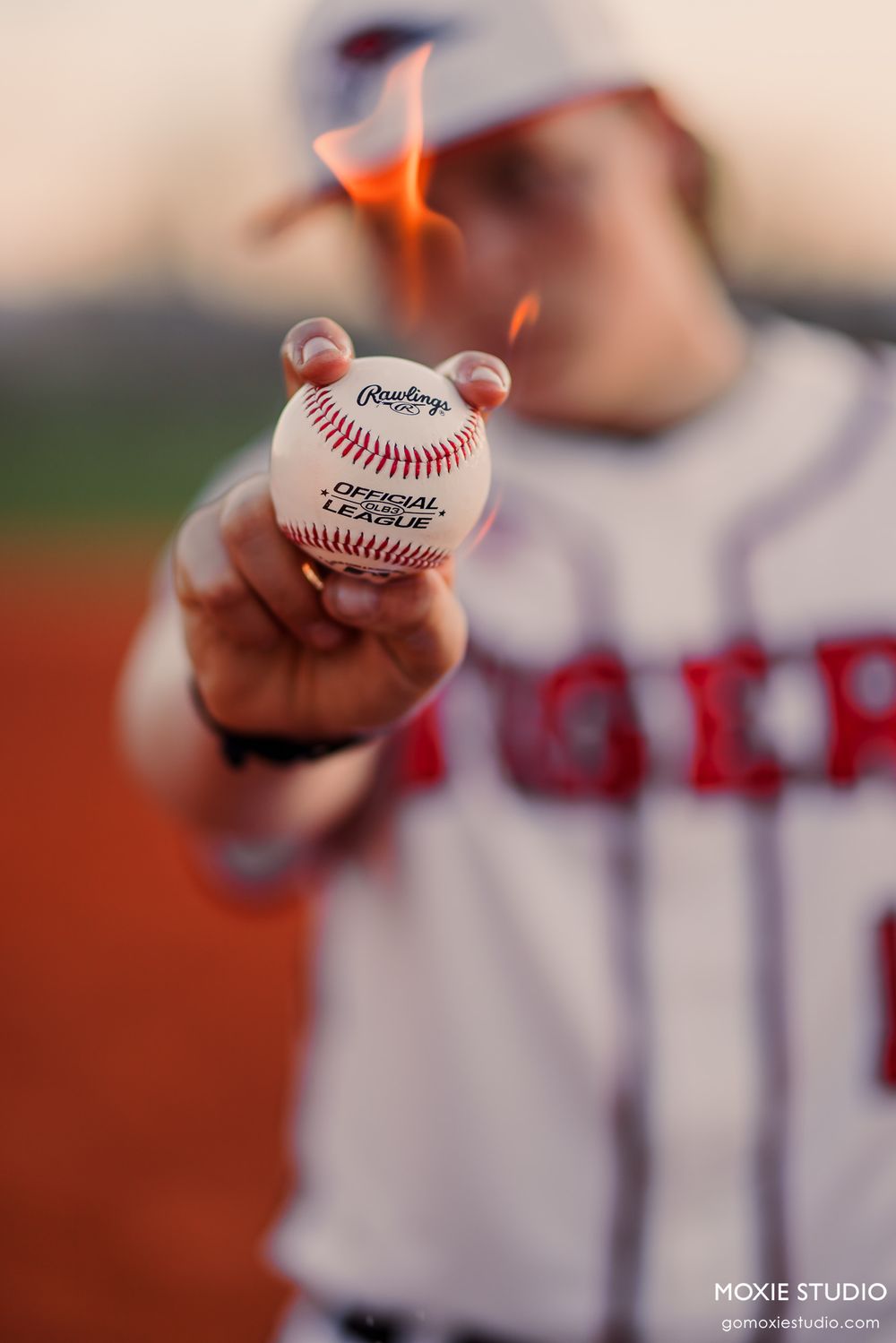 Close-up shot of baseball player holding an official Rawlings baseball in Angels uniform against blurred background.