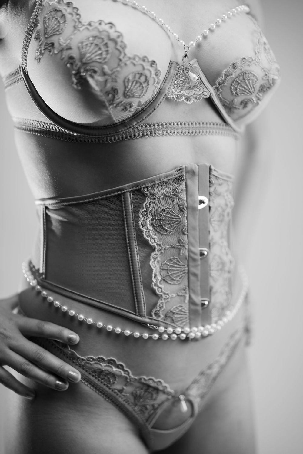Black and white photo series showing details of an elegant lace corset with pearl trim and delicate boning details.