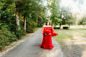 A red backpack sits on a winding forest path surrounded by lush green trees and foliage in natural lighting.