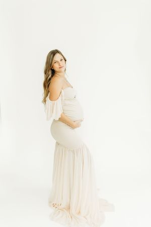 Soft and romantic maternity photos in a light pink flowing dress.