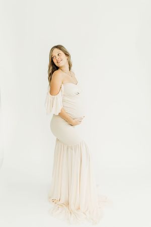 Ethereal maternity portrait in cream-colored off-shoulder gown with ruffle details.
