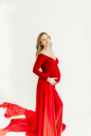 Dynamic maternity portrait featuring a vibrant red dress with flowing fabric movement.